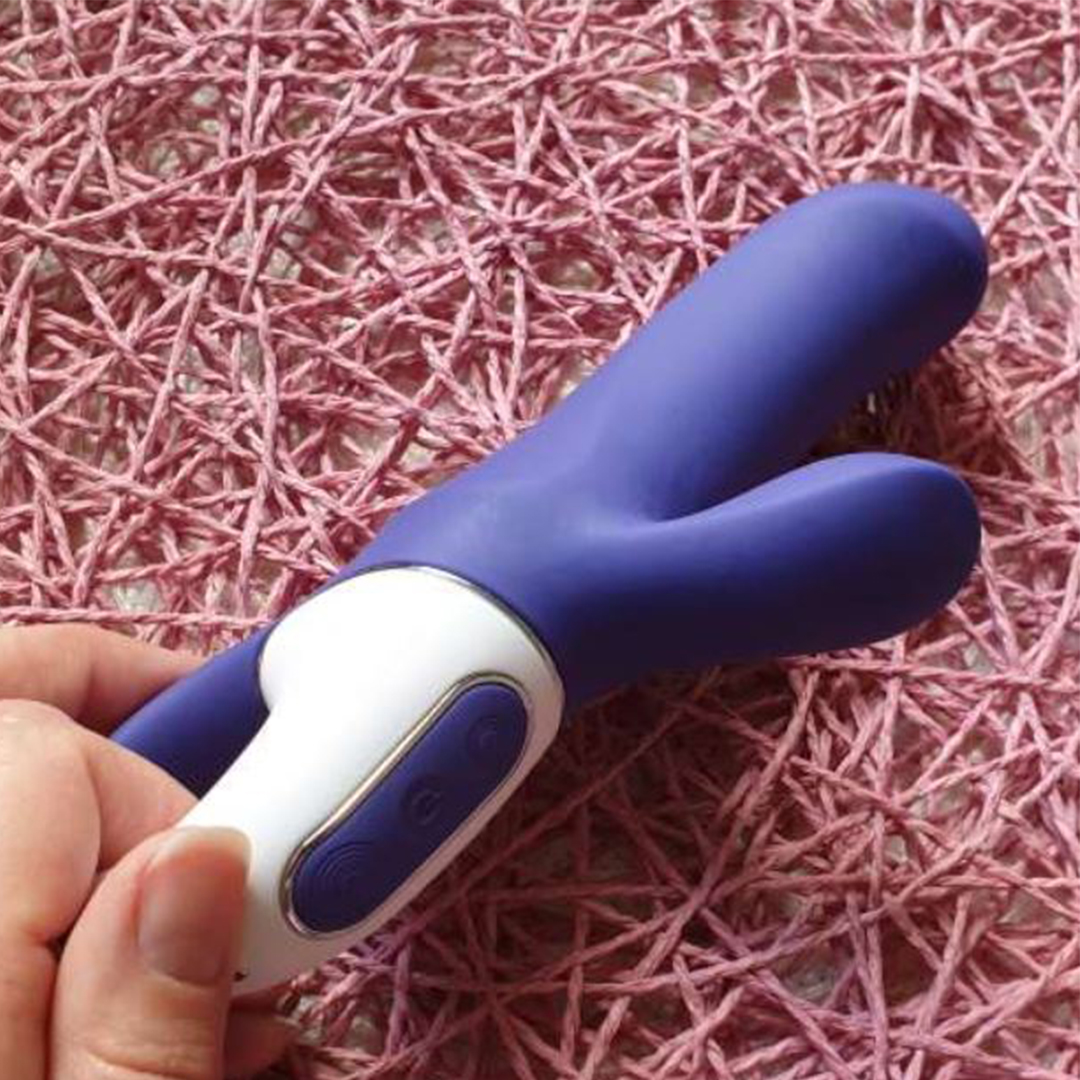 Dvigubas vibratorius "Magic Bunny" – Violetinis 
 
Kartu su dviem varikliukais „Satisfyer“ vibratorius „Magic Bunny“  lepina ne tik jūsų G tašką, bet užtikrina ir klitorio stimuliaciją.  
  
Išlinkusi, ilgesnė dalis tiksliai pasiekia G tašką, o klitorio stimuliatorius priglunda prie klitorio. Visas malonumą suteikiantis prietaisas yra iš  kokybiško, minkšto silikono,  kuris „Magic Bunny“ vibratoriui suteikia itin didelį lankstumą ir švelnumą liečiant, bet ir gilias vibracijas, kurios stipriai perduodamos jūsų „karštiesiems“ taškams. 
Patogus laikiklis užtikrina patogų naudojimą. Rankenoje esantį valdymo laukelį galima valdyti visiškai intuityviai – galima rinktis iš  12 vibracijų programų, kurias sudaro 6 intensyvumo lygiai ir 6 vibracijos  – tikrai rasite tinkamą, jūsų nuotaiką atitinkančią programą. 
  
Vibratorius yra  atsparus vandeniui  ir dėl to puikiai tinka naudoti vonioje ar romantiškoje sūkurinėje vonioje. Jei žaisliukas išsikrauna, akumuliatorius galima pakartotinai įkrauti pridėtu  USB  įkrovimo laidu.  
Tinkamai prižiūrint  šis vibratorius tarnaus tikrai ilgai. Prieš ir po kiekvieno naudojimo nuplaukite jį šiltu vandeniu ir švelniu muilu arba specialiu žaislų valikliu. Leiskite išdžiūti natūraliai. Šį sekso žaislą laikykite stalčiuje, specialiame maišelyje arba kitoje vietoje, kurioje nėra dulkių. Laikykite jį atokiau nuo kitų sekso žaislų. Nepalikite tiesioginiuose saulės spinduliuose ir niekada nelaikykite jo dideliame karštyje. 
  
Rekomenduojama naudoti kartu su vandens pagrindo lubrikantu.  Nenaudokite silikoninių lubrikantų, aliejų ar kremų, nes jie gali sugadinti prietaiso medžiagą ir apriboti jo veikimą bei galiojimo laiką.  
Dvigubo vibratoriaus naudojimo būdai:  
Kai kurios moterys naudoja dvipusius vibratorius seksui su antrąja moterimi. Dildo dvigubas galas leidžia vienu metu prasiskverbti į dvi makštis.  
Nuo makšties iki išangės. Dauguma dvigubo įsiskverbimo dildo yra skirti tuo pačiu metu stimuliuoti išangės ir makšties erogenines zonas, tačiau pailgintų dvigubų vibratorių atveju du partneriai gali naudoti tą patį žaisliuką vienu metu.   
Išangė į išangę. Dauguma dvipusių dildo gali būti naudojami abiejų partnerių analiniam įsiskverbimui.  
Imituojamą oralinį seksą taip pat galima atlikti su dvipusiu vibratoriumi.  
Kodėl jums reikalingas vibratorius? 
Vibratorius ar klasikinis vibratorius yra sekso žaislas, naudojamas ant kūno maloniai seksualinei stimuliacijai kelti. 
Vibratoriai gali būti naudojami tiek solo, tiek poroje ar kelių žmonių žaidimams kartu. Taip pat jie gali būti naudojami erogeninėms zonoms, tokioms kaip klitoris, vulva ar makštis, varpa, kapšelis ar išangė, siekiant seksualiai stimuliuoti, išlaisvinti seksualumą ir pasiekti orgazmą. 
Vibratoriai yra rekomenduojami sekso terapeutų moterims, kurioms sunku pasiekti orgazmą masturbacijos ar lytinių santykių metu.